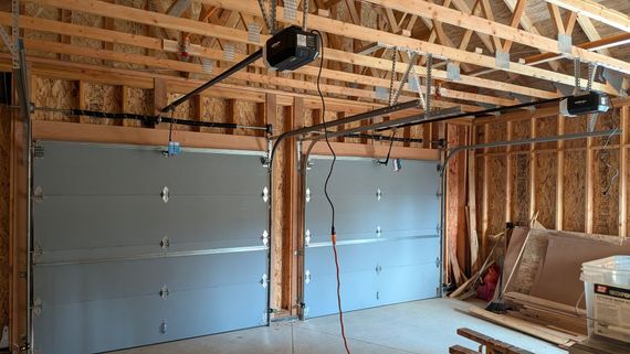 Framed garage interior under construction with insulated garage doors and exposed ceiling beams