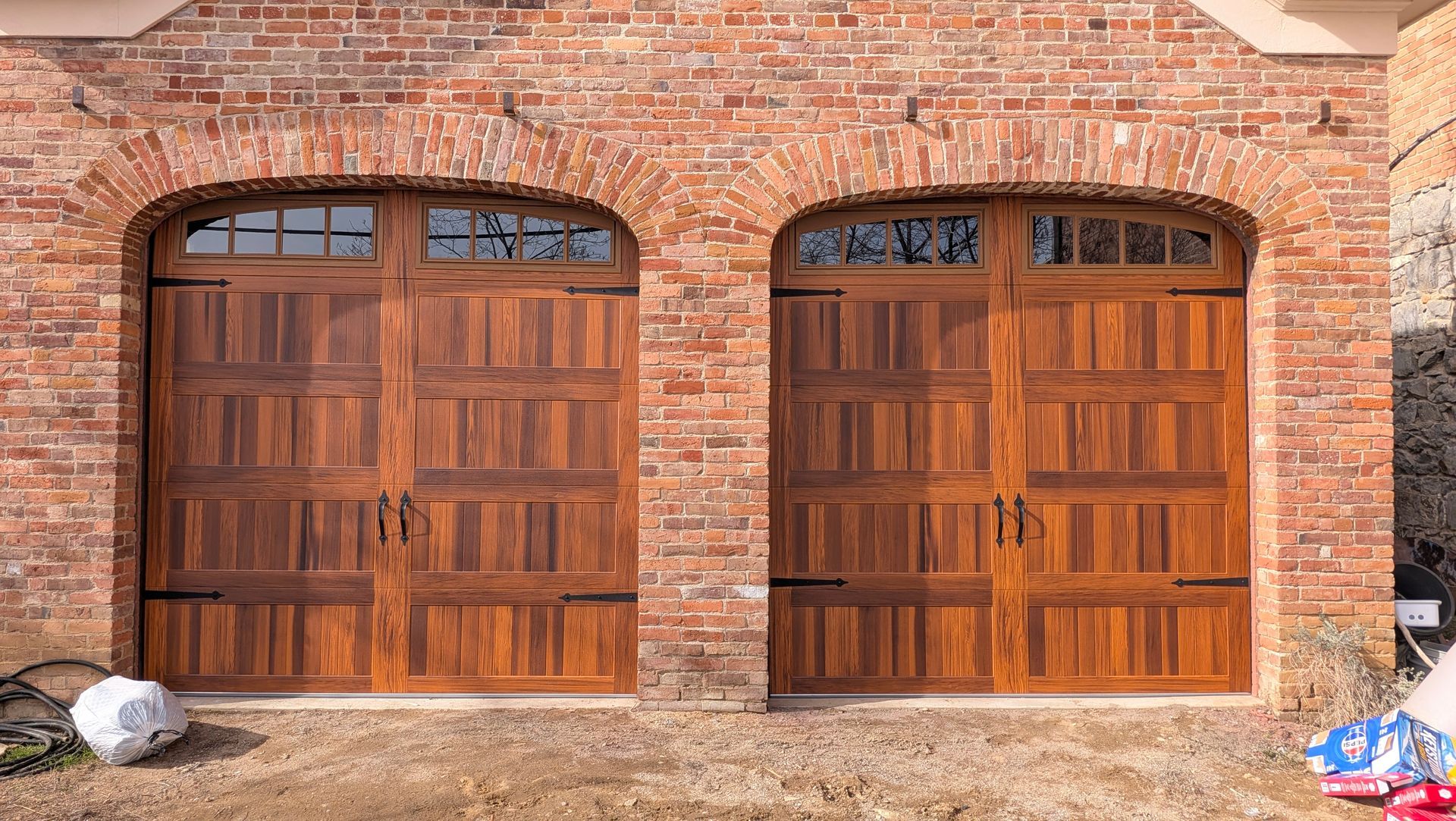 Two wooden garage doors set in a red brick building facade.