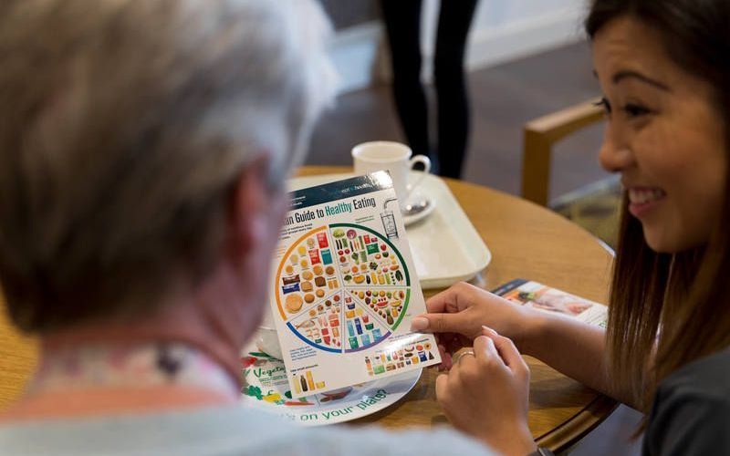 A woman is sitting at a table talking to an elderly man.