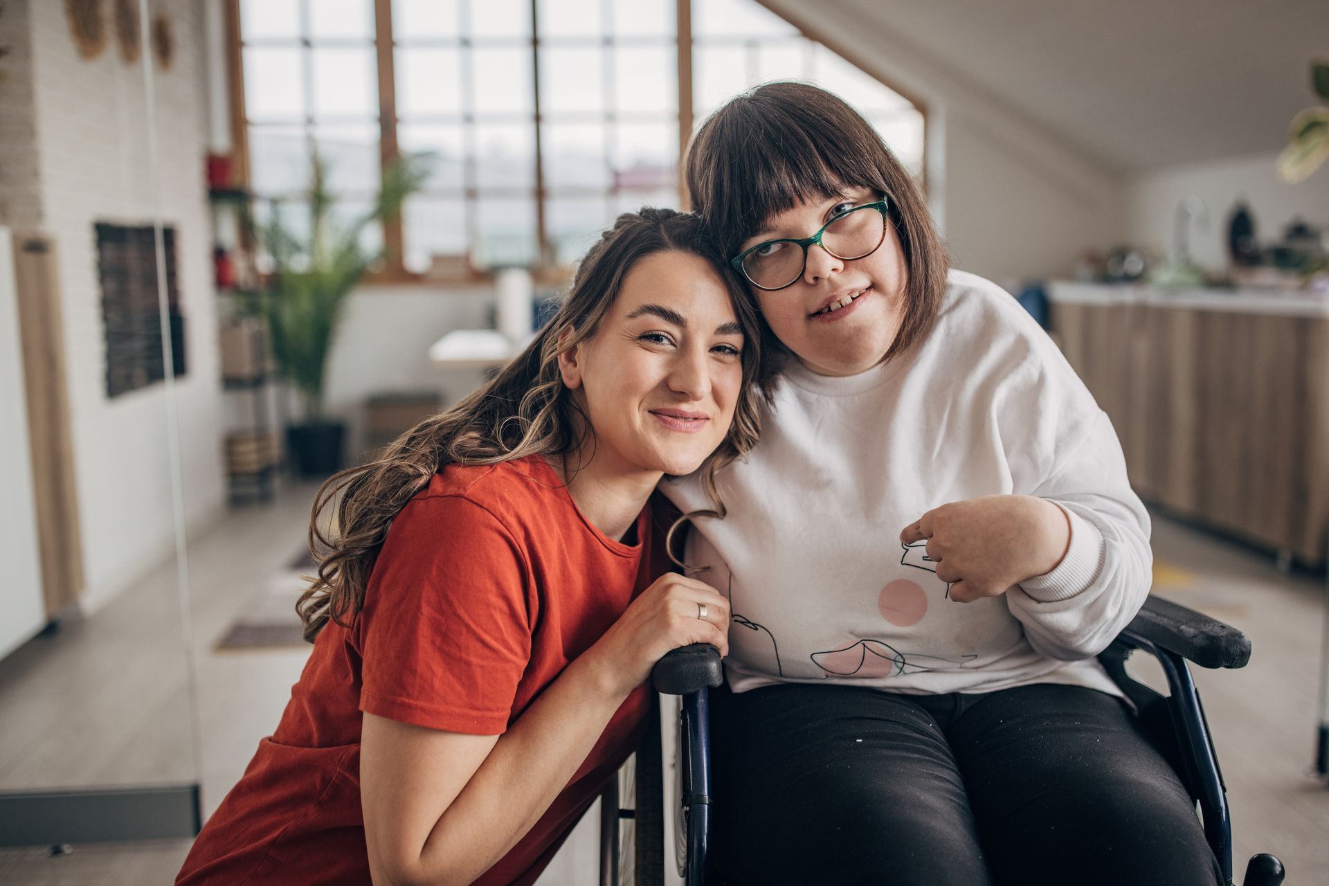 A woman is sitting next to a woman in a wheelchair.