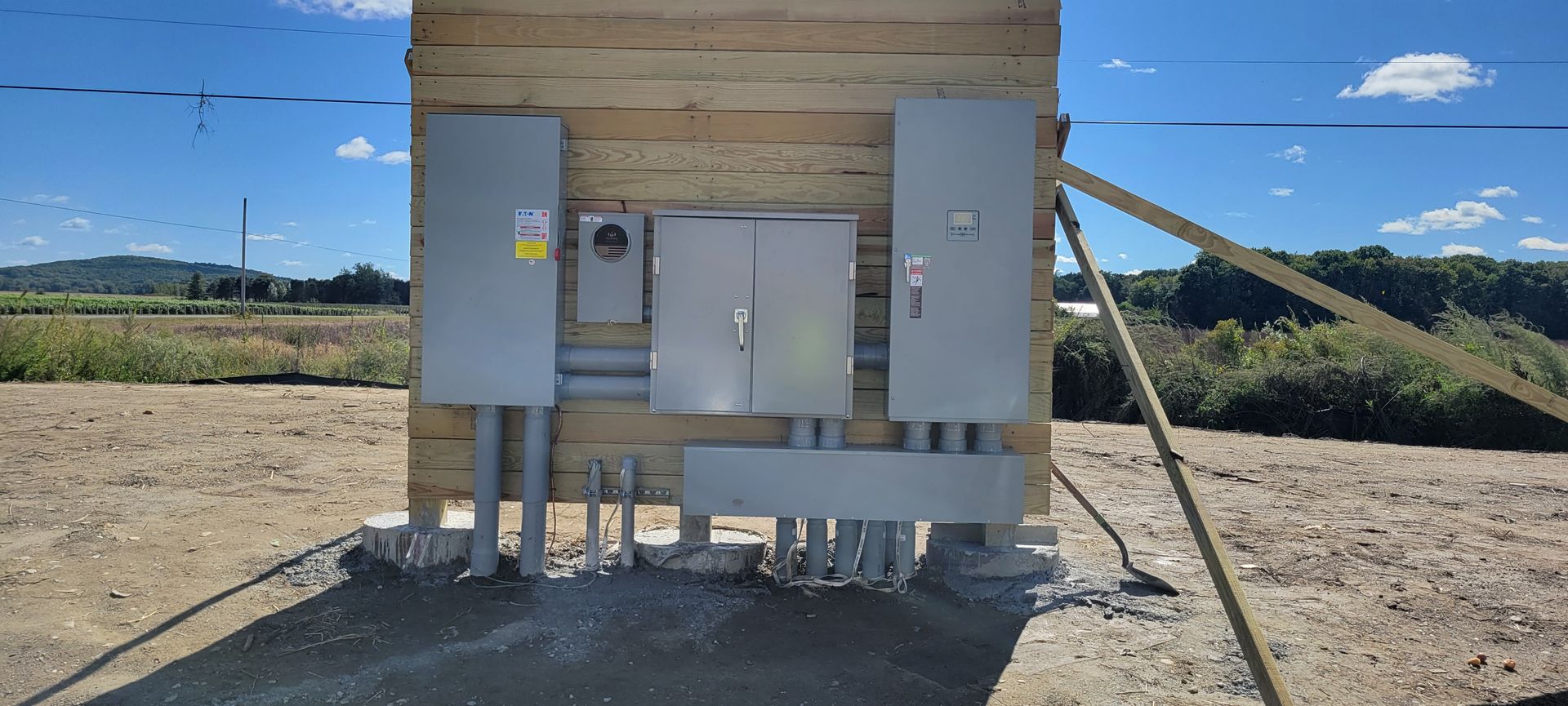 A large electrical box is sitting in the middle of a dirt field.