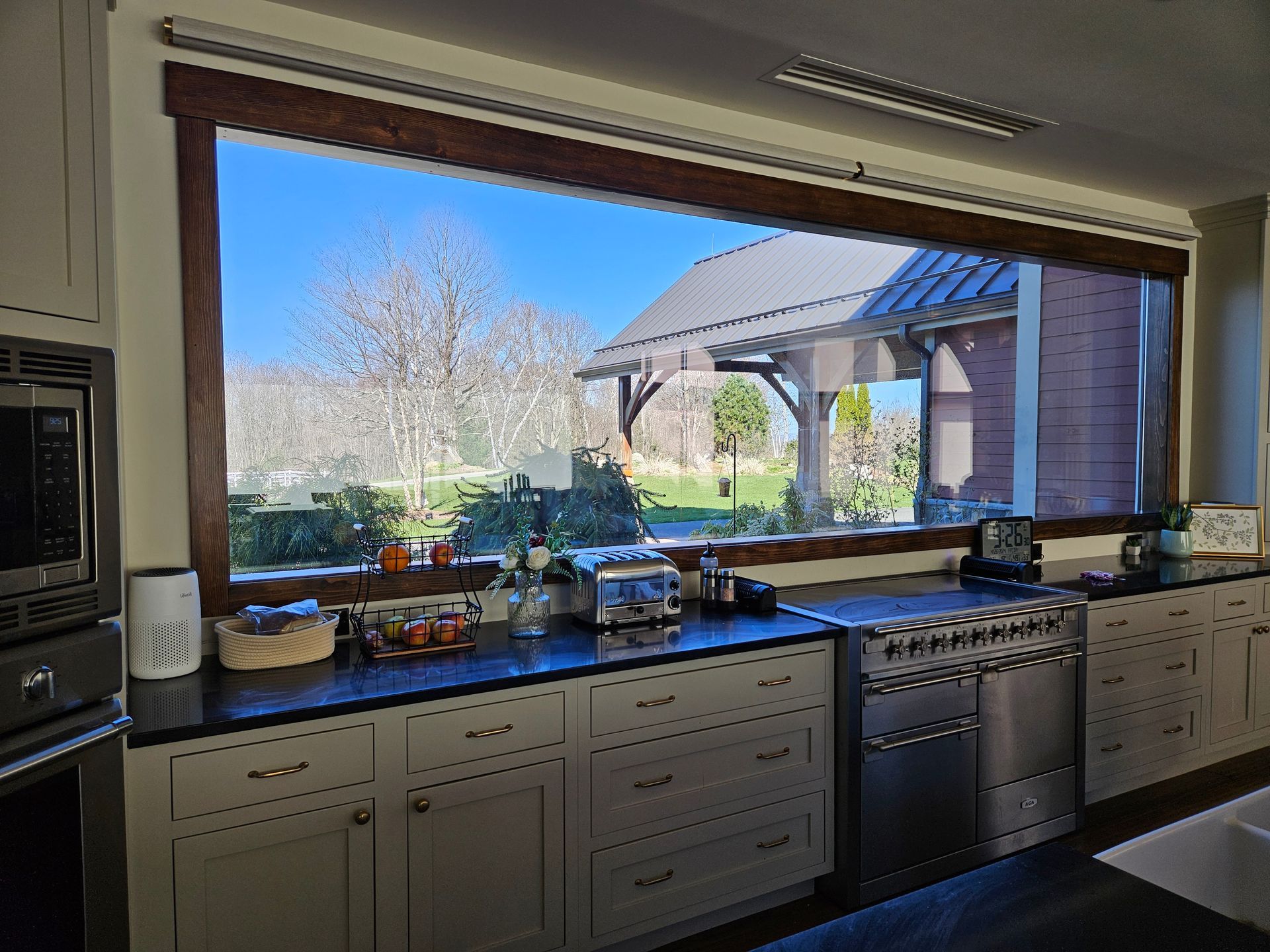 A kitchen with a large window looking out to a yard.