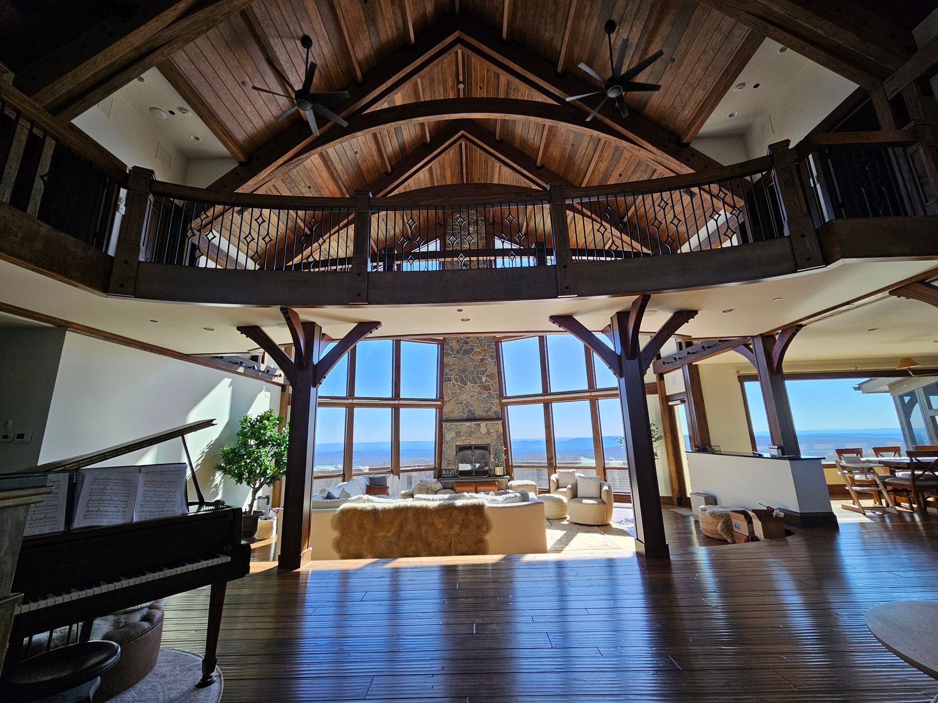 A large room with a piano and a balcony overlooking the ocean