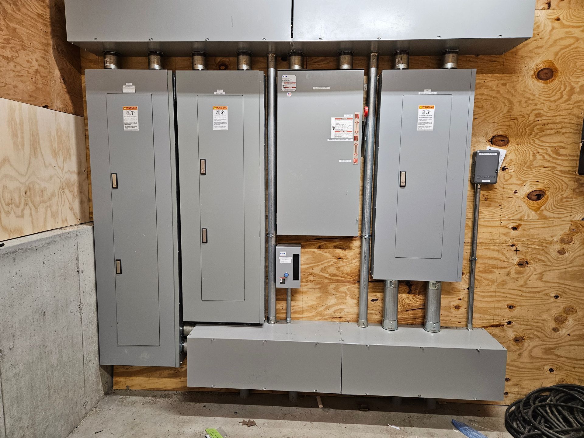 A bunch of electrical panels are hanging on a wall in a room.
