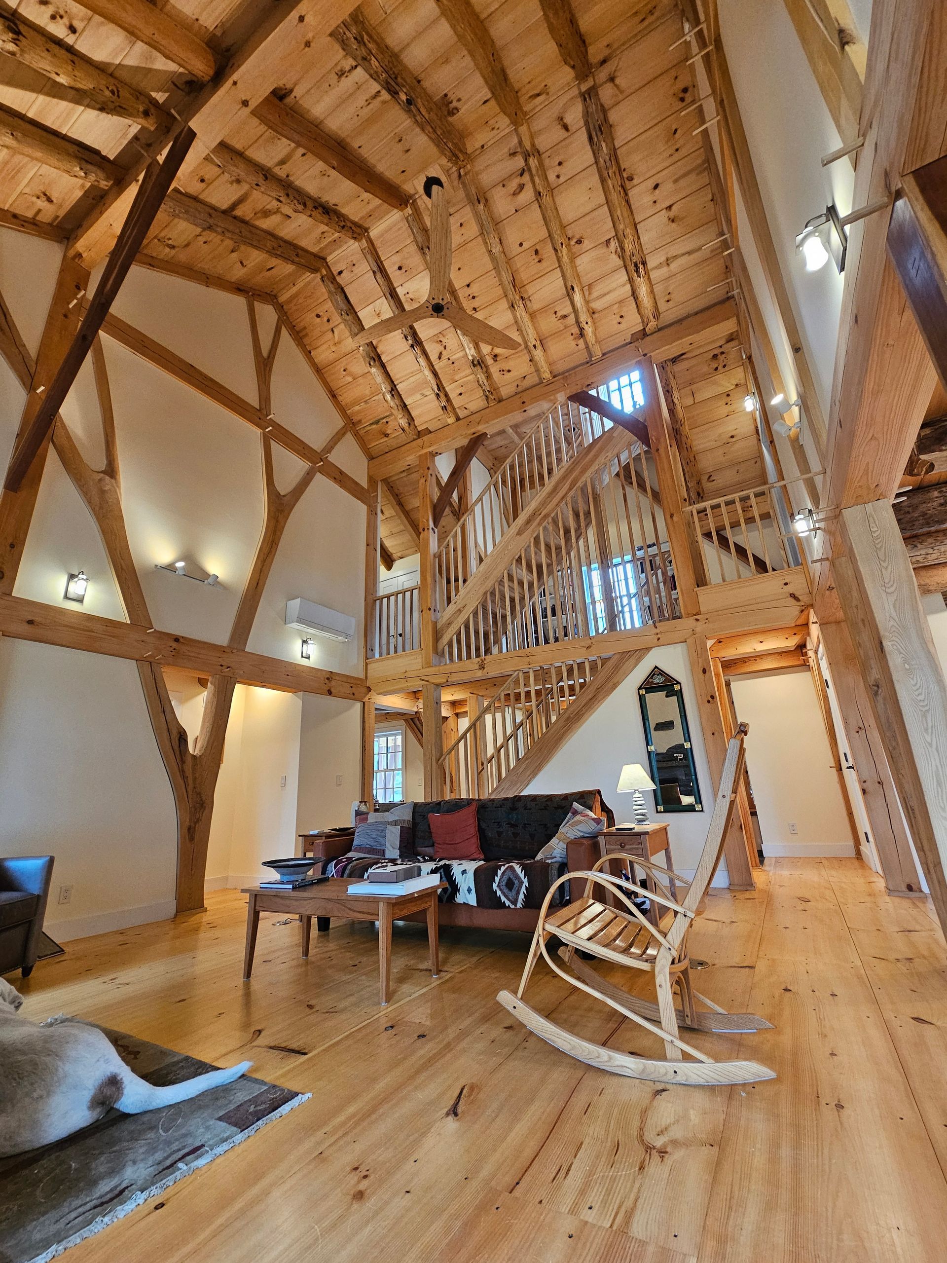A living room with a rocking chair , couch , table and stairs.