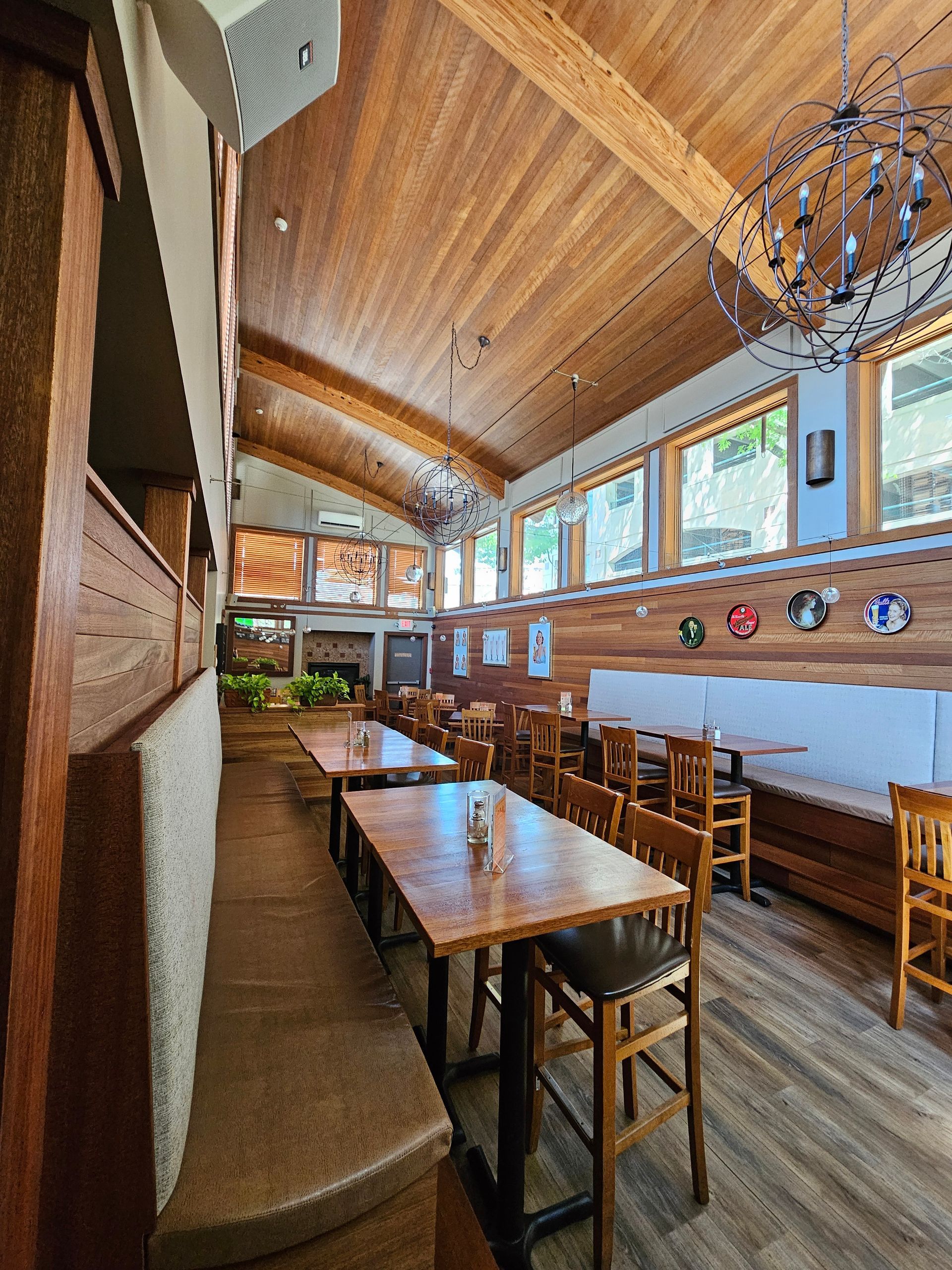 A restaurant with wooden tables and chairs and a chandelier.
