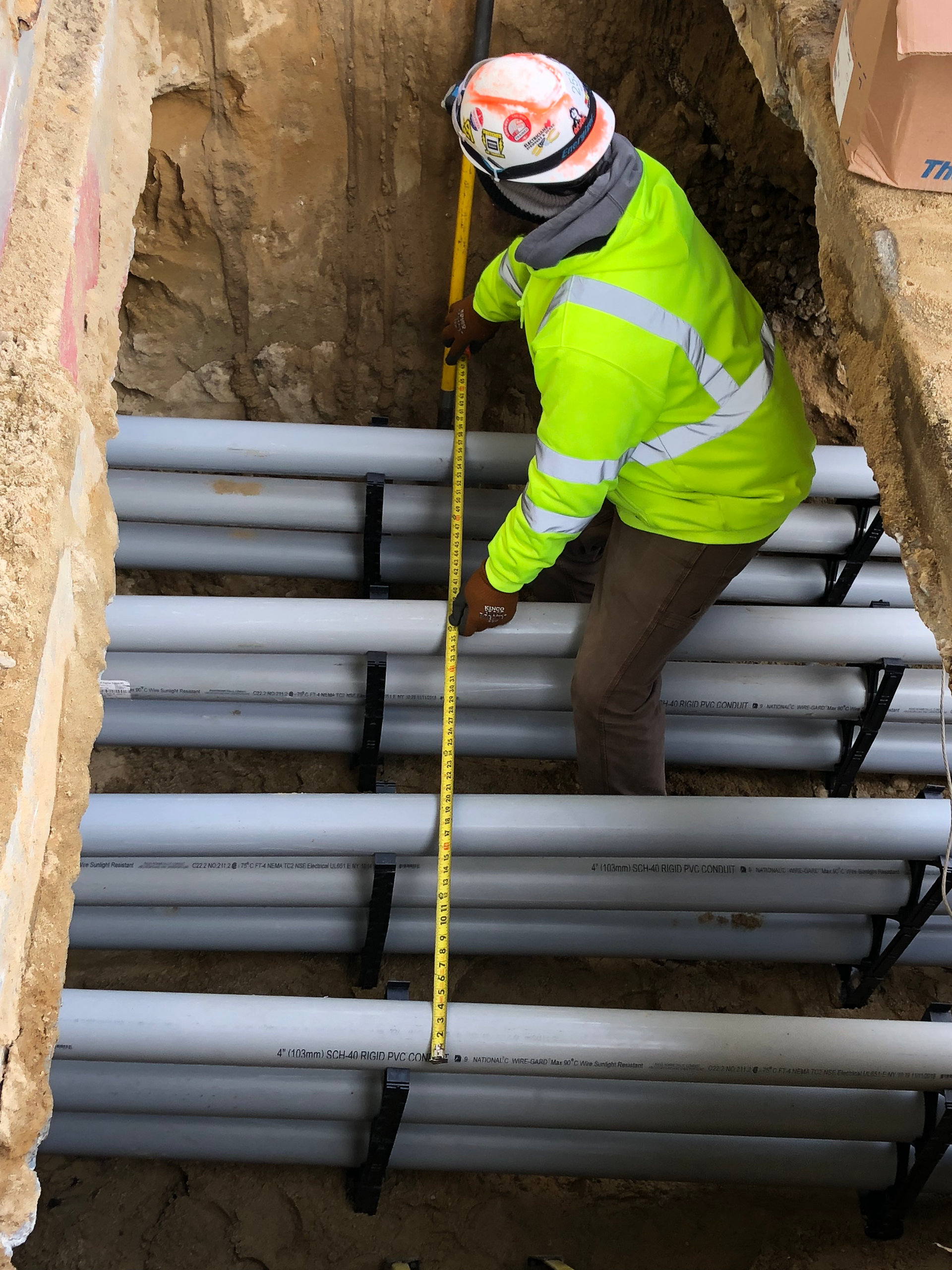 A man is measuring a bunch of pipes with a tape measure