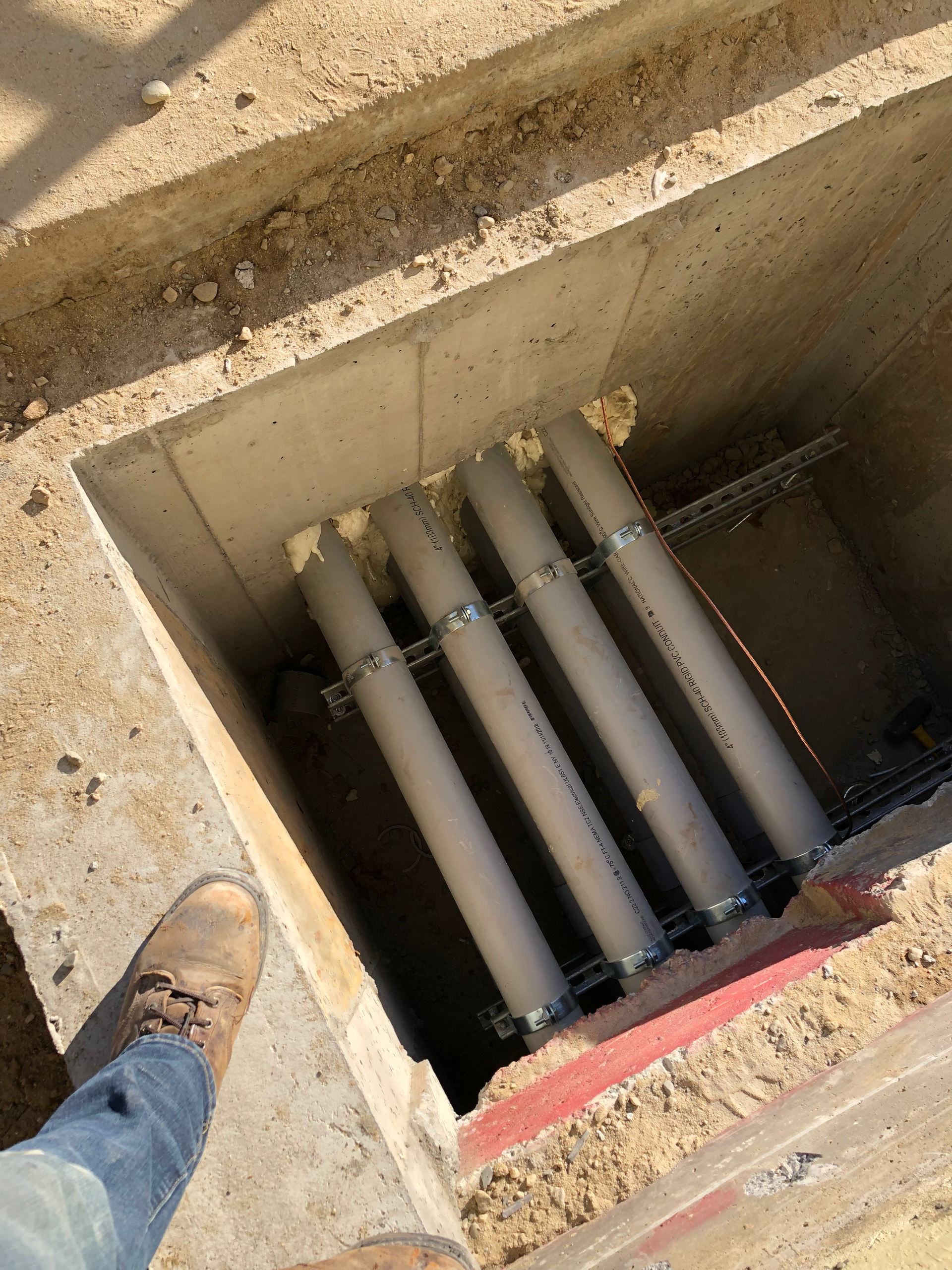 A person is standing in a hole with pipes in it.