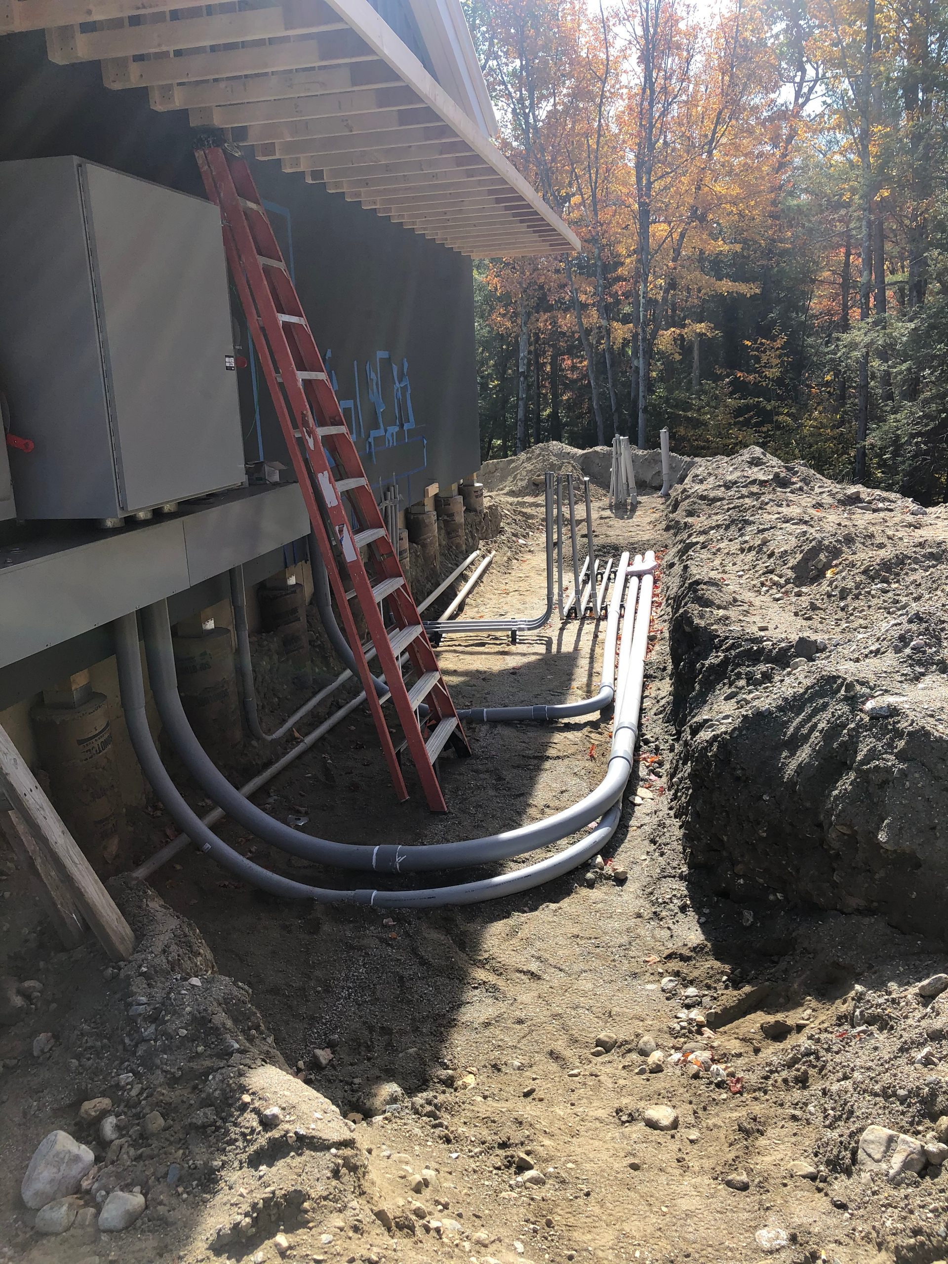 A ladder is sitting in the dirt next to a house under construction.