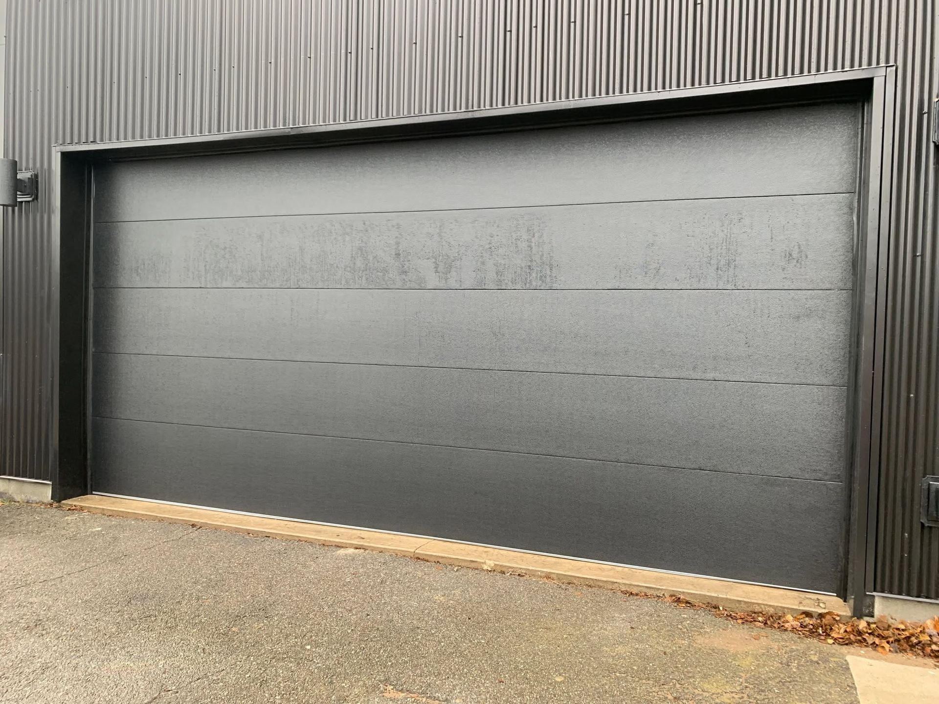 Closed gray garage door on a corrugated metal building