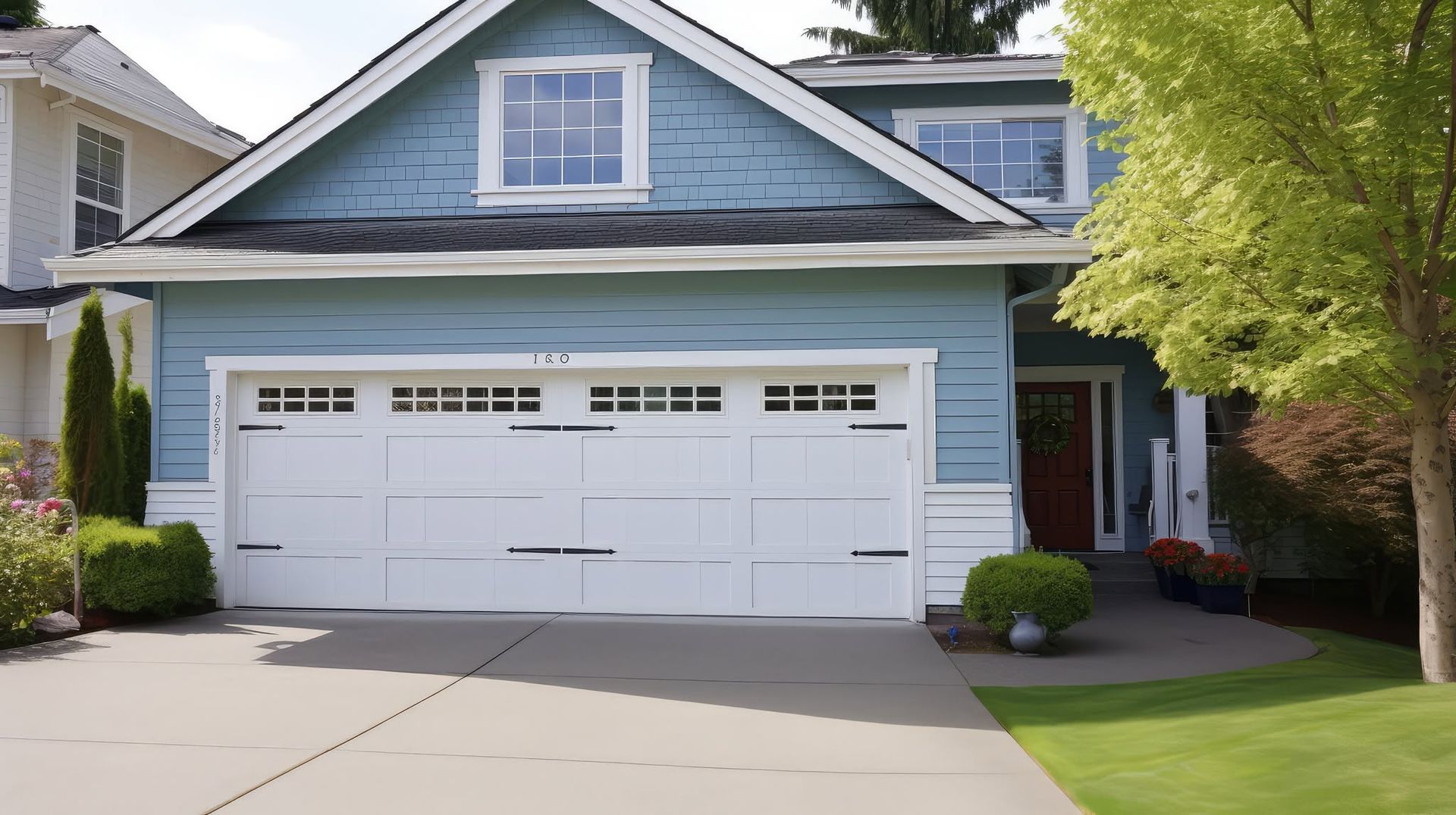 Blue two-story house with a white garage and front lawn under sunny skies