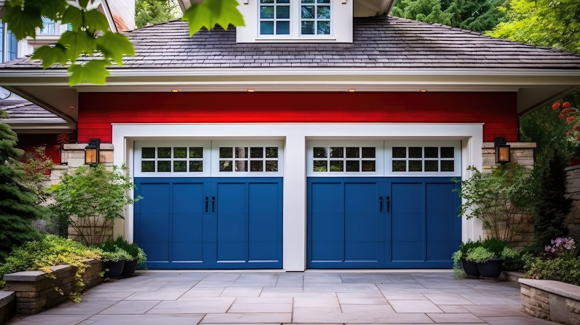 Blue double garage doors on a house with red trim and greenery above the driveway