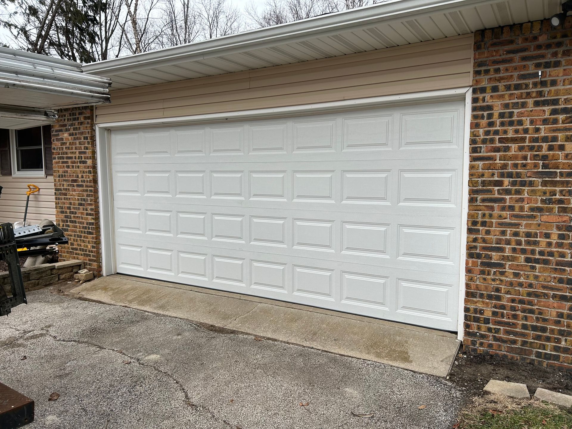 White double garage door on a brick house with a concrete driveway and driveway apron
