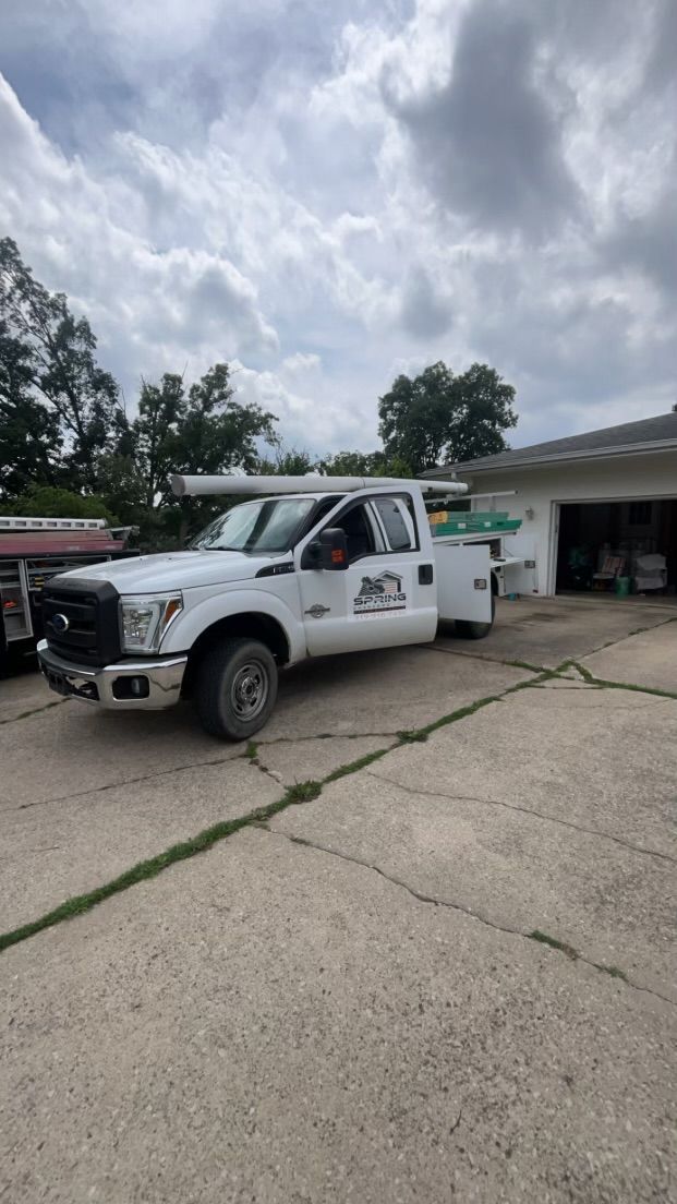 White utility truck parked outside a building on a cracked concrete lot under cloudy skies.