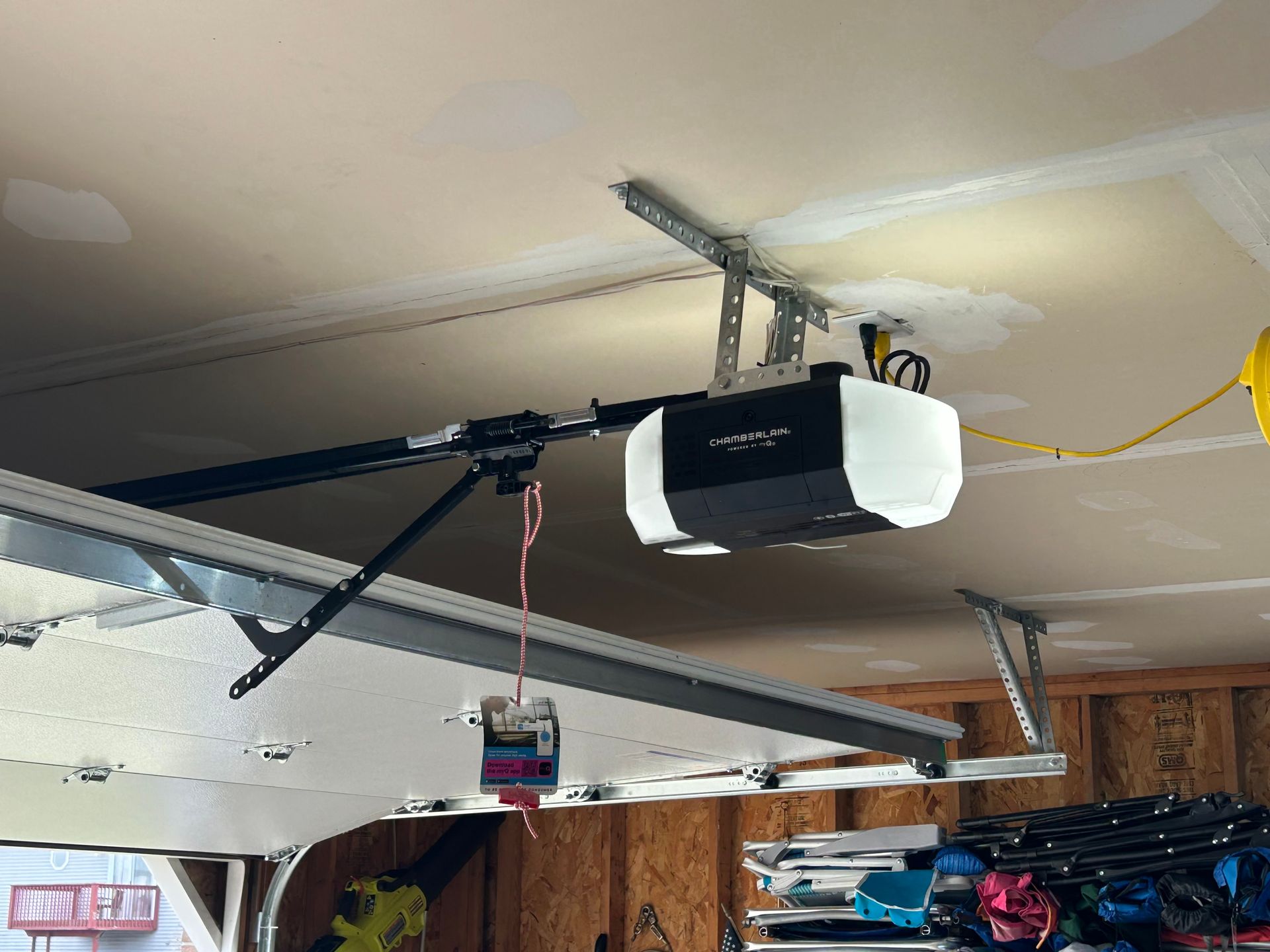 Ceiling-mounted garage door opener on a black track in a garage interior.