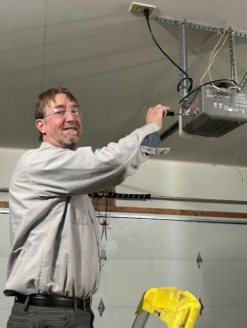 Man in a garage reaching up to adjust a ceiling-mounted garage door opener