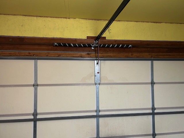 Garage door interior with metal tracks, dark wood trim, and a yellow wall above.