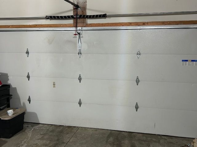 Closed white garage door with metal handles and ceiling opener rails inside a garage