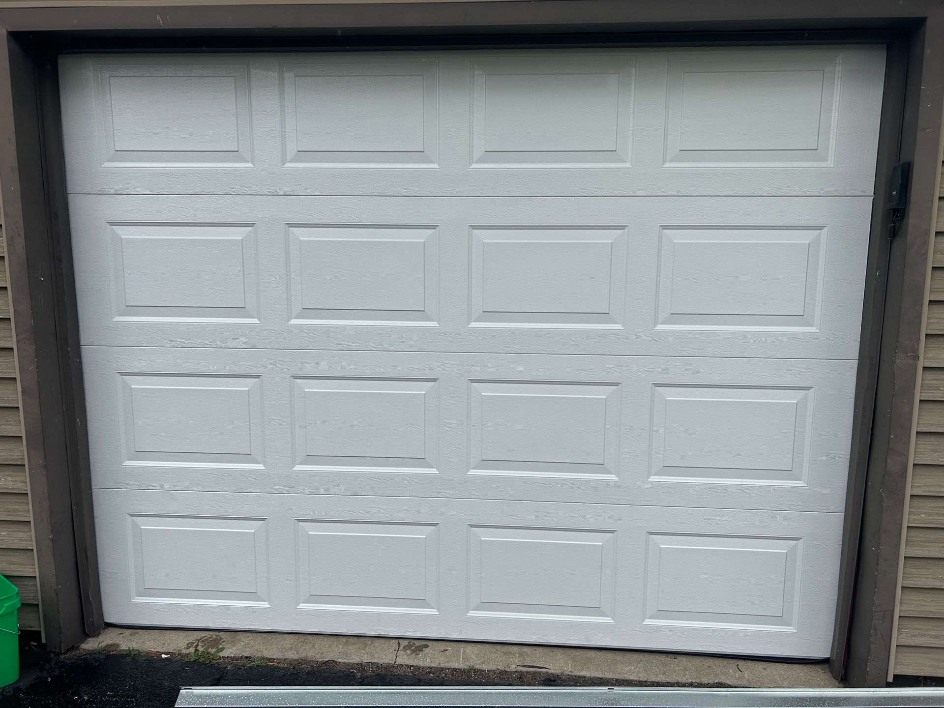 White sectional garage door in a beige driveway opening