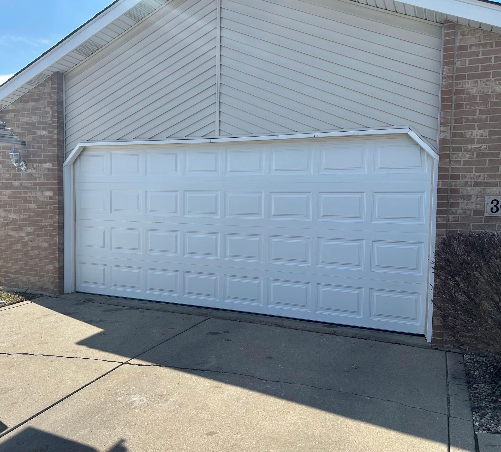 White double garage door on a brick house with a concrete driveway in front.