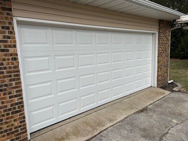 White paneled garage door on a brick house with a concrete driveway