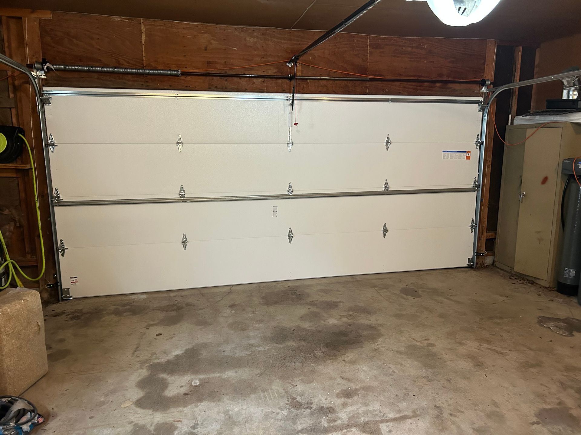 Empty garage with a closed white double garage door and concrete floor.