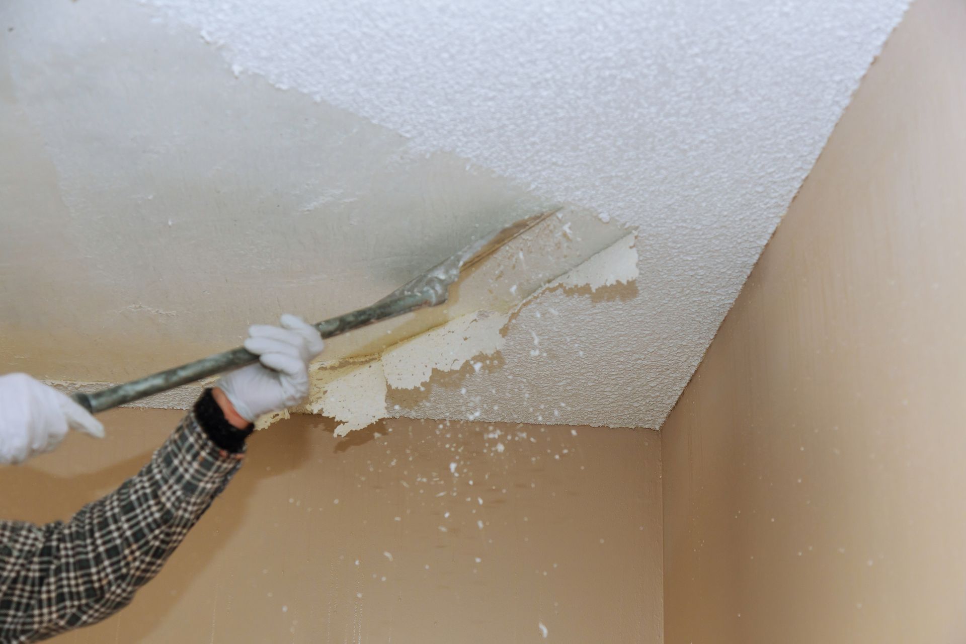 Two construction workers are working on a wall in a building under construction.