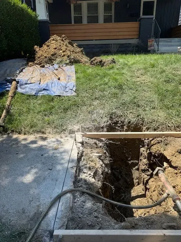 Blue and white pipes installed along a house foundation, draining rainwater into the yard.