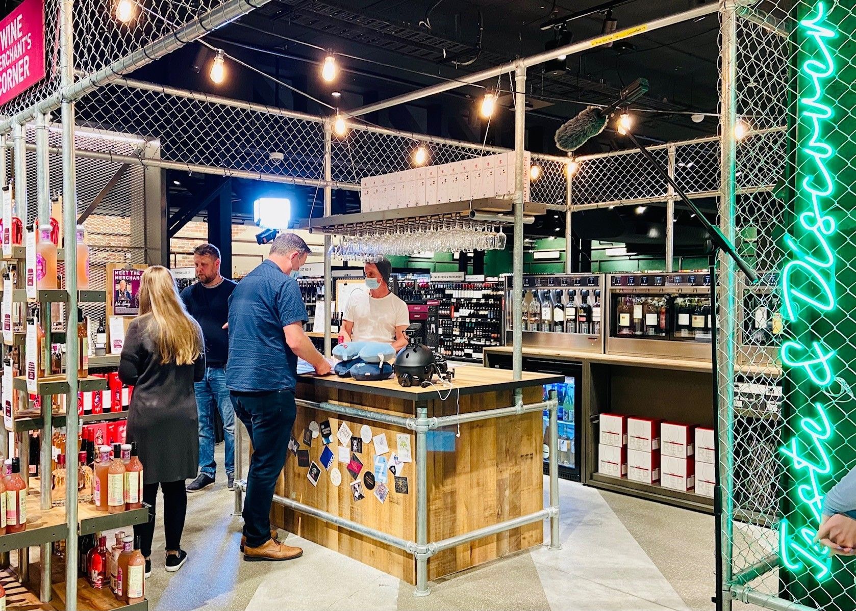 A group of people are standing around a wooden bar in a restaurant.