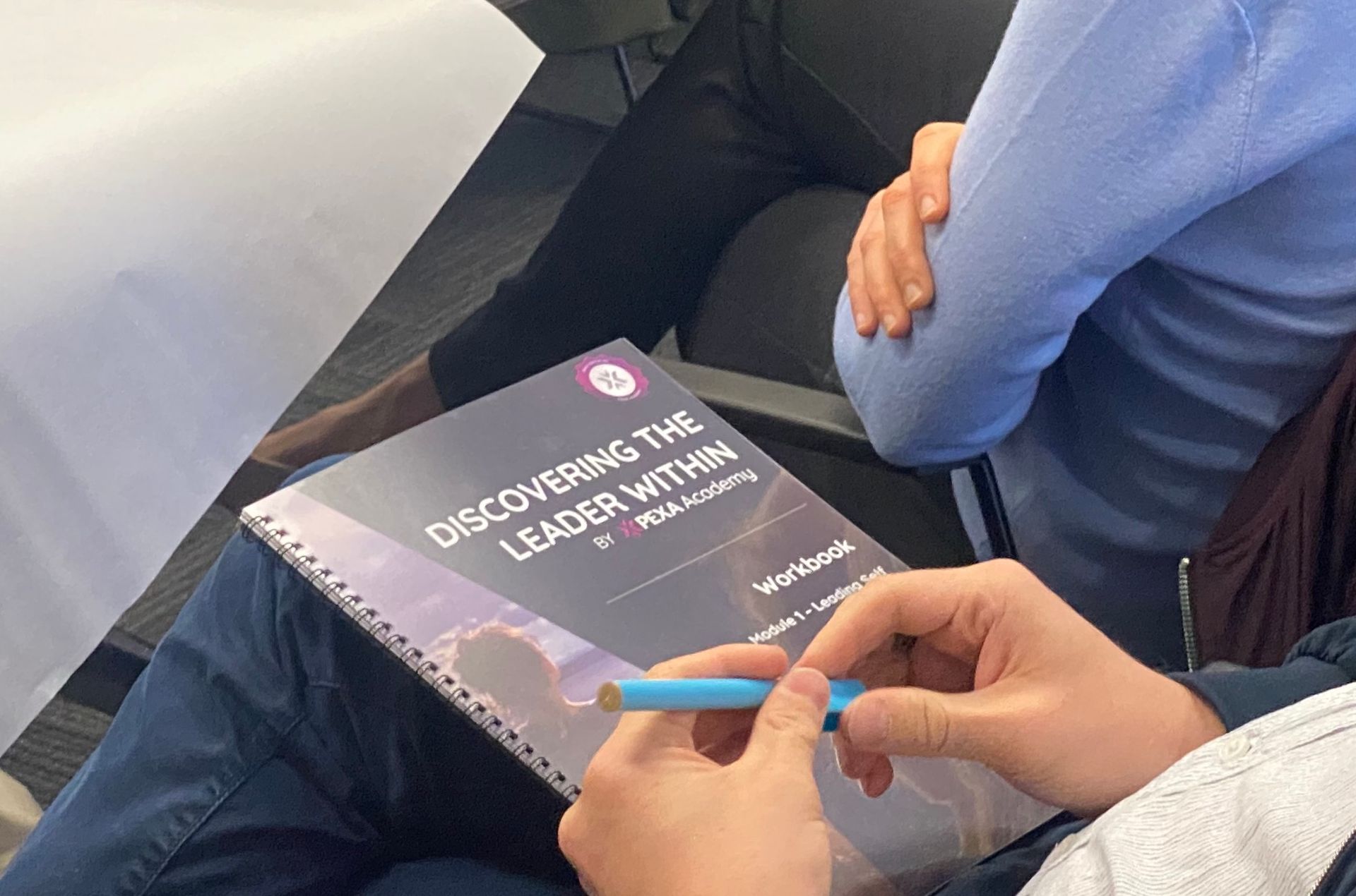 A person is holding a book titled discovering the leader within.