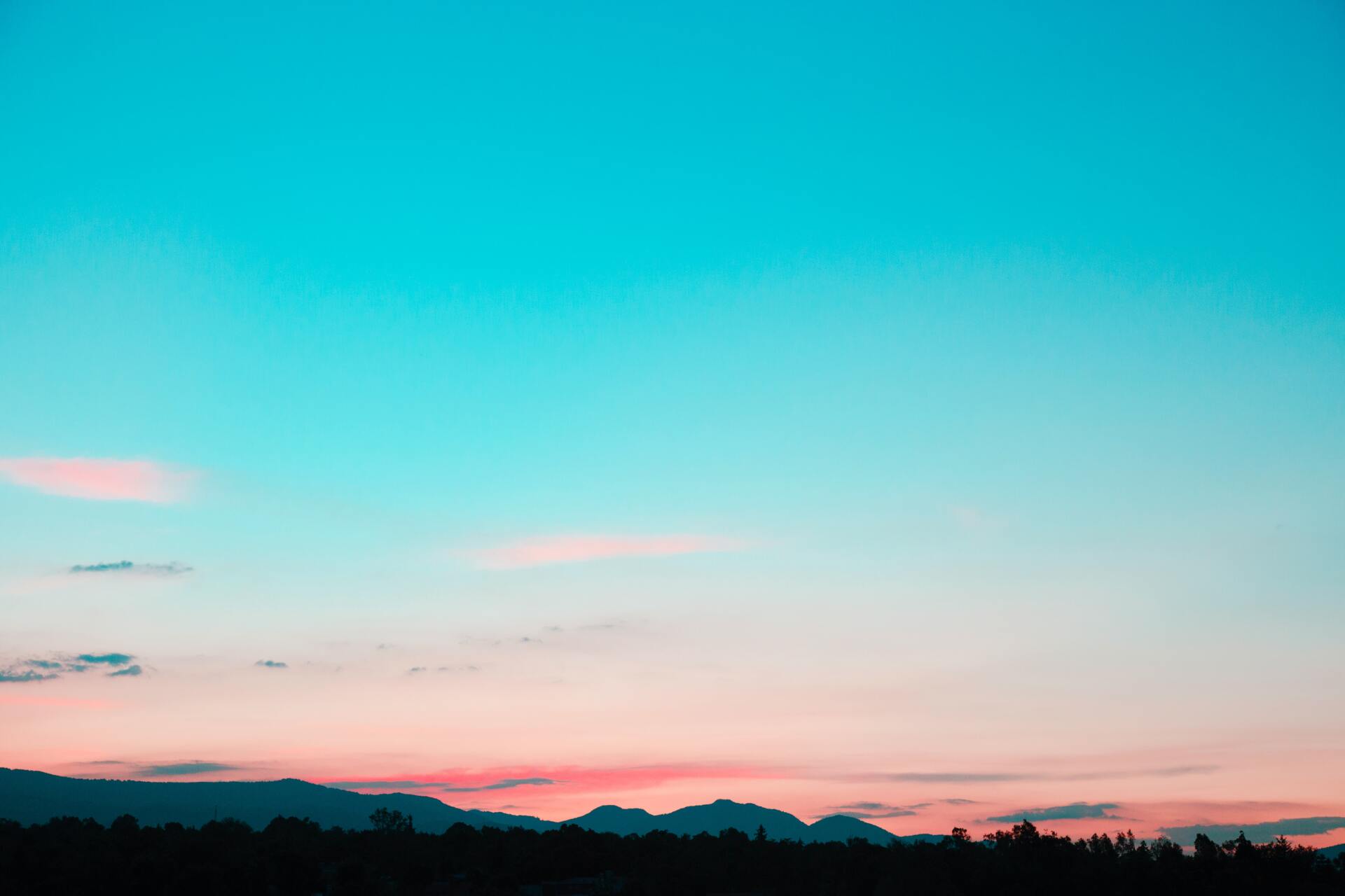 A sunset over a forest with mountains in the background