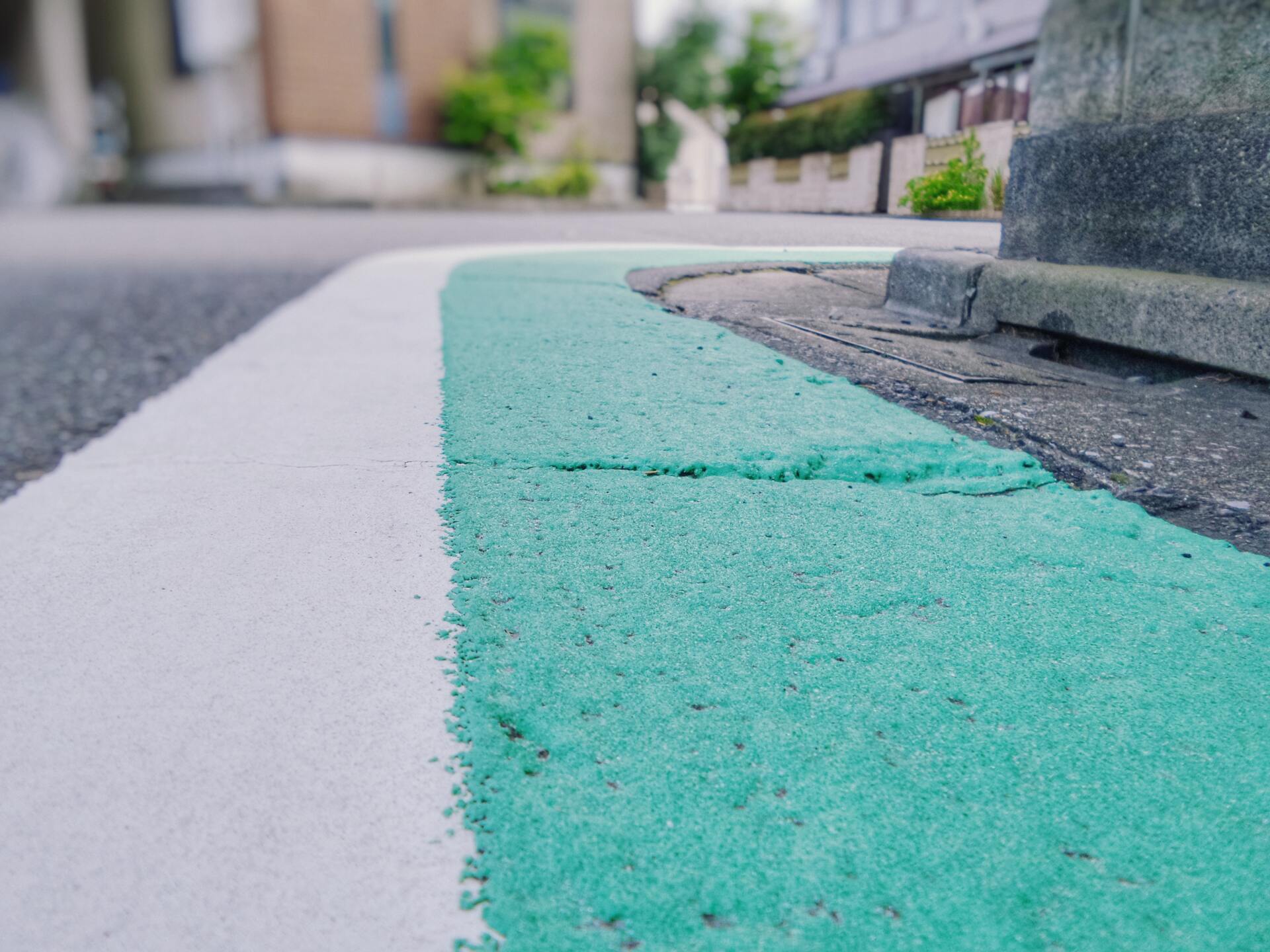 A close up of a green and white line on a sidewalk.