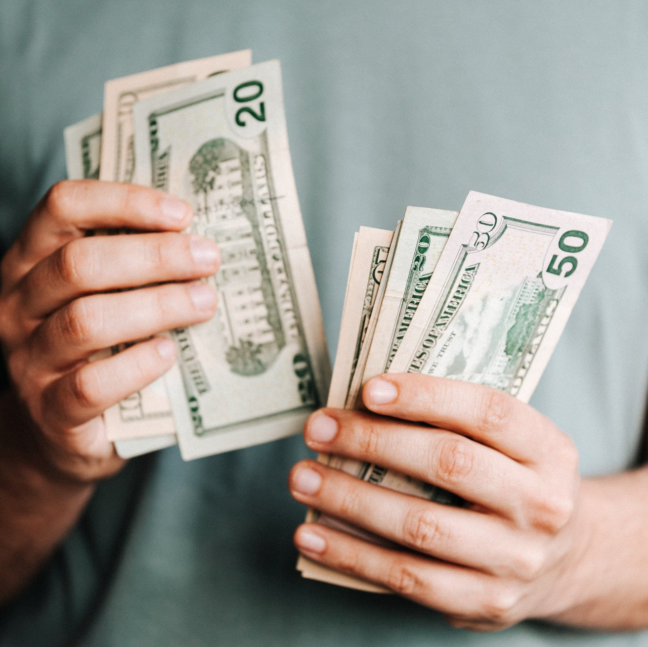 A person is holding a bunch of money in their hands.