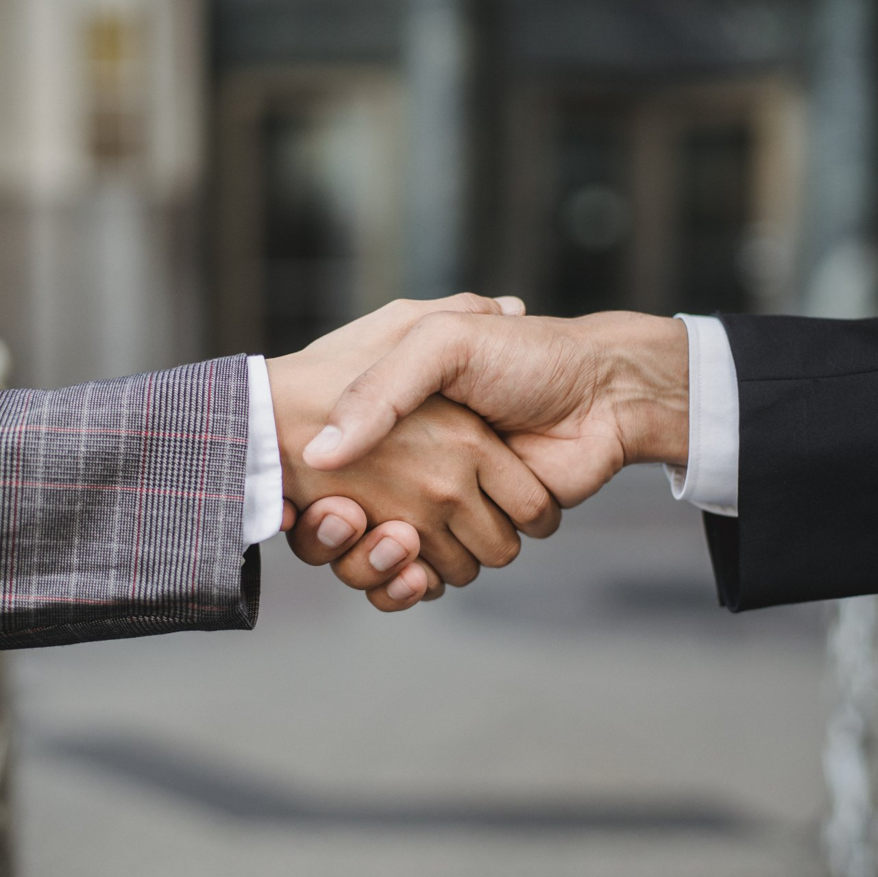 A man and a woman are shaking hands in front of a building.