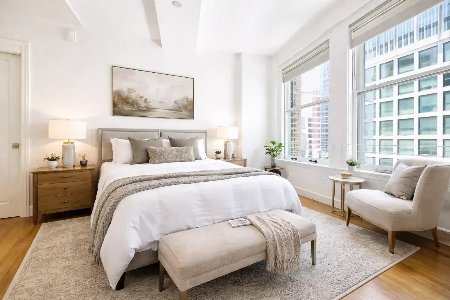 Bright bedroom in a one-bedroom apartment at HWH Luxury Living with large windows, hardwood floors, and modern furnishings.