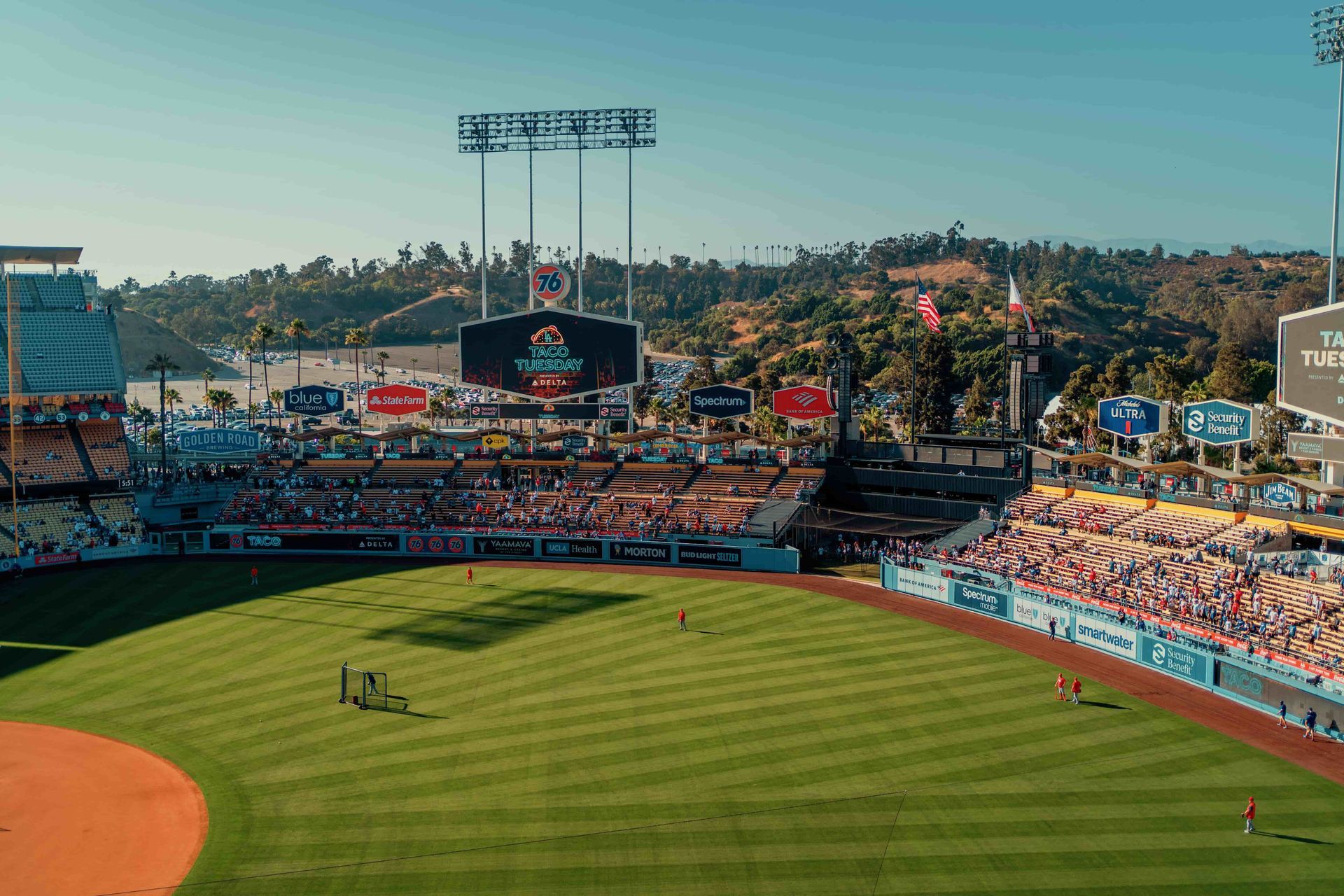 Dodger Stadium in Los Angeles with the baseball field, seating areas, scoreboard, and surrounding hills visible on a sunny day.