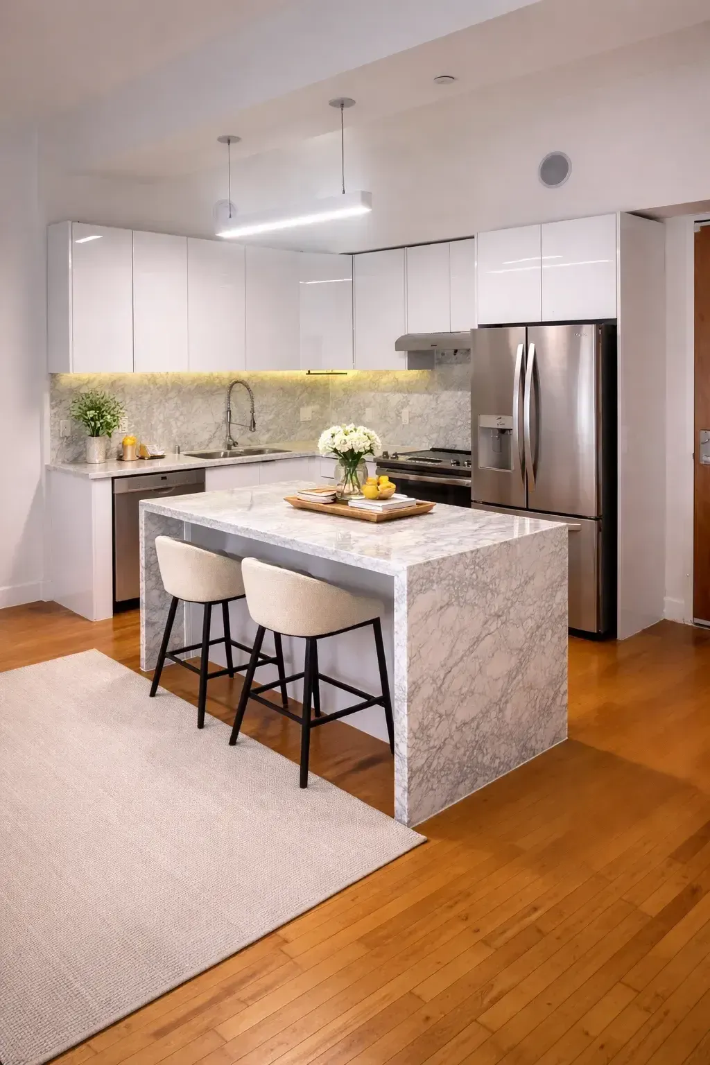 Modern kitchen in a one-bedroom apartment at HWH Luxury Living with marble island, white cabinetry, and stainless steel appliances.