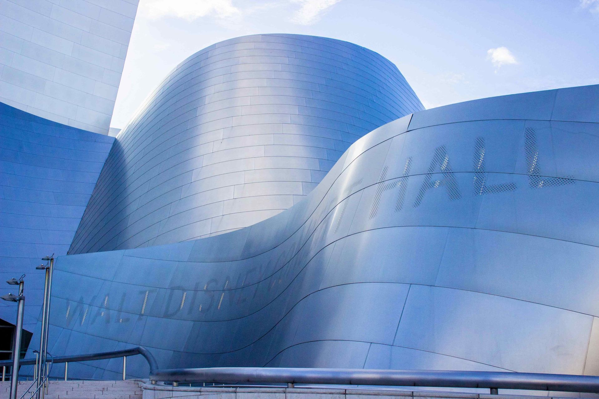 Walt Disney Concert Hall in downtown Los Angeles, showing the building’s curved silver architecture and exterior walkway on a sunny day.