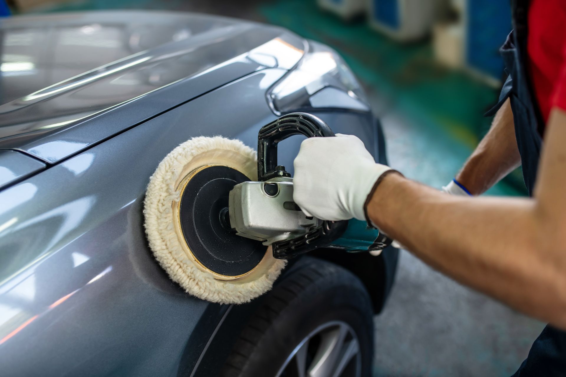 A close-up of a male hand with a polishing machine on a surface of a car. A close-up of a male hand with a polishing machine on a surface of a car.