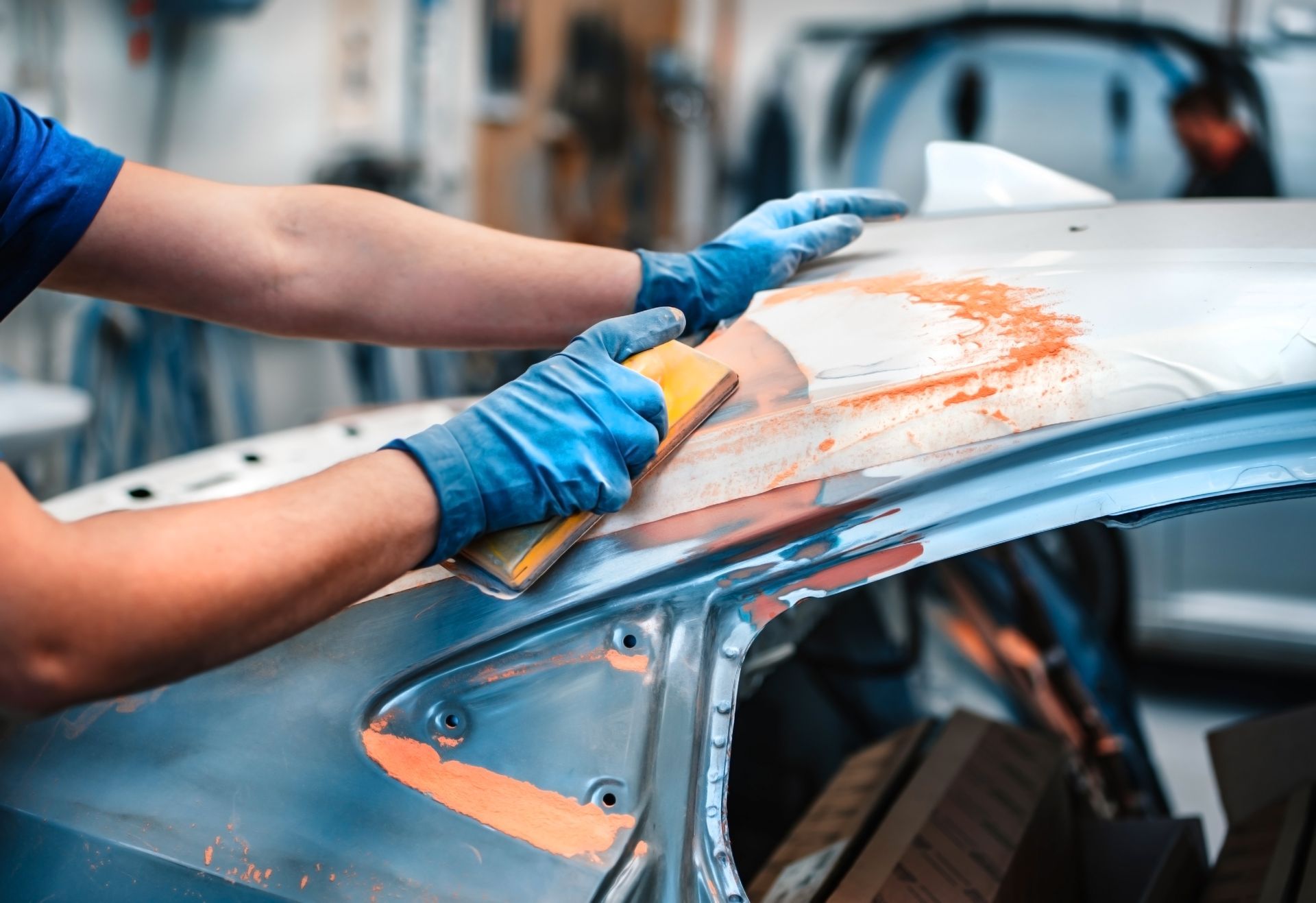 Automotive technician performing smash repair on a damaged car in a workshop.