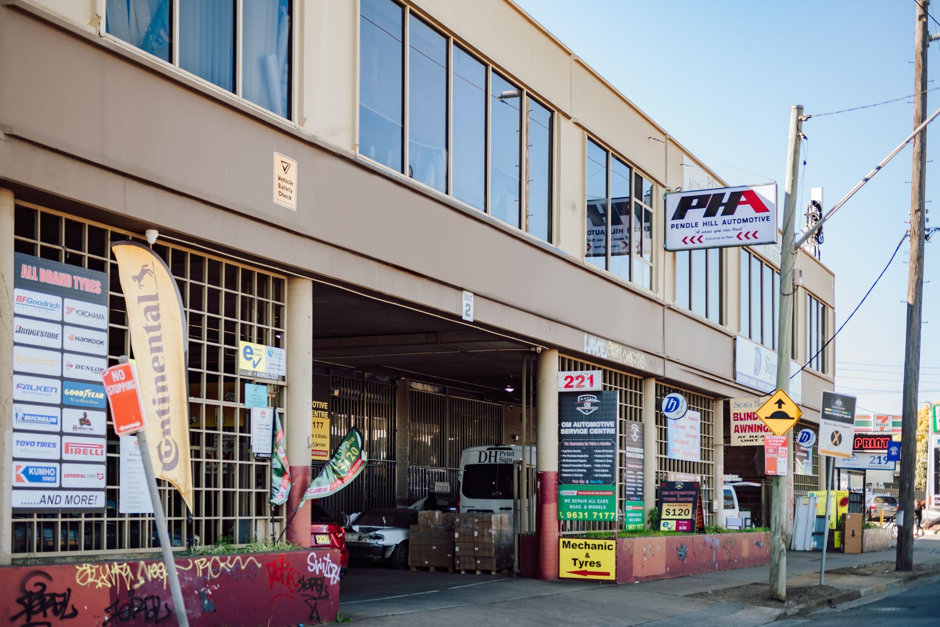 A tire shop with a tan facade and a covered entrance. Various tire brands are advertised on the building's exterior.