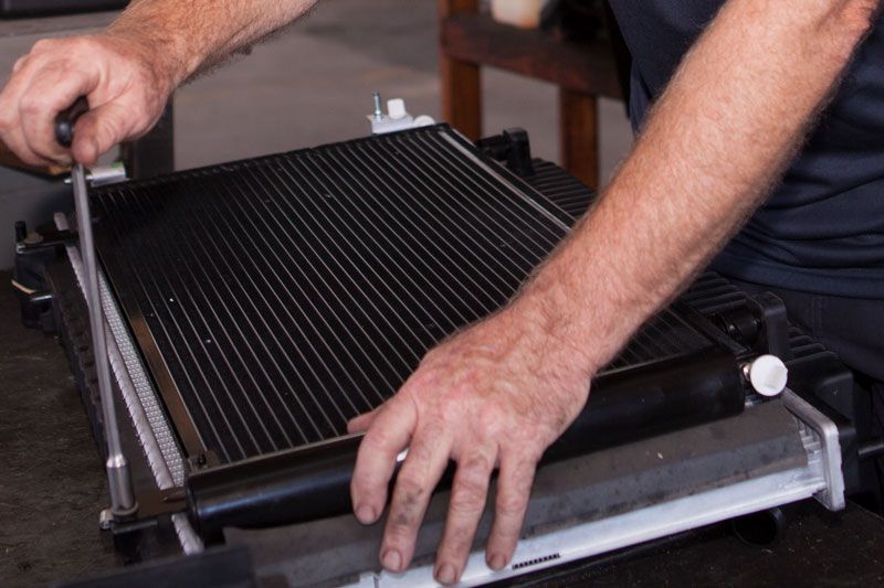 Mechanic using a tool to assemble a car radiator.