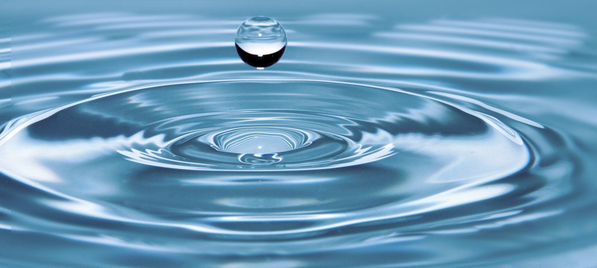 A water droplet falling into a body of water, creating ripples.