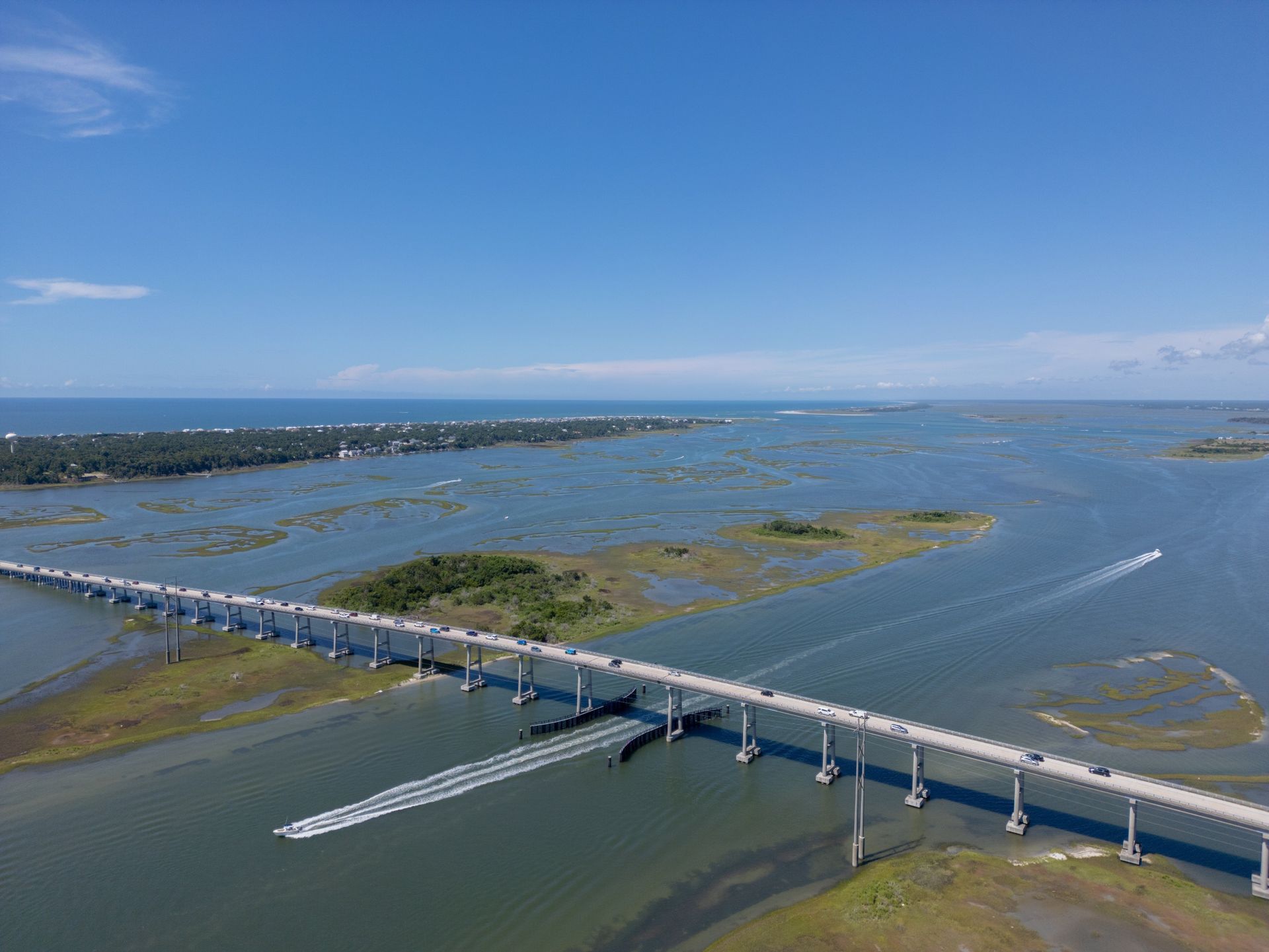 Aerial view of a long bridge over blue water and marshland under a clear sky