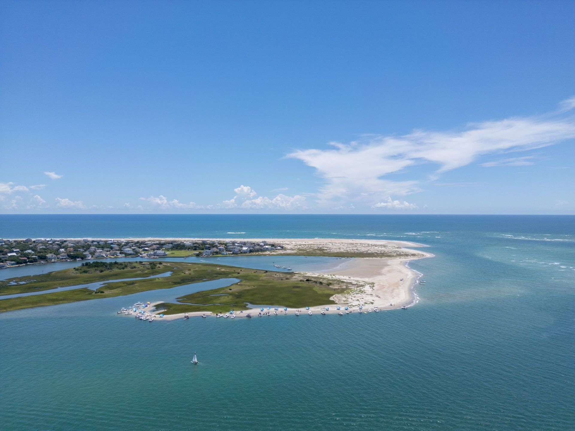 Aerial view of a sandy island and turquoise ocean under a blue sky