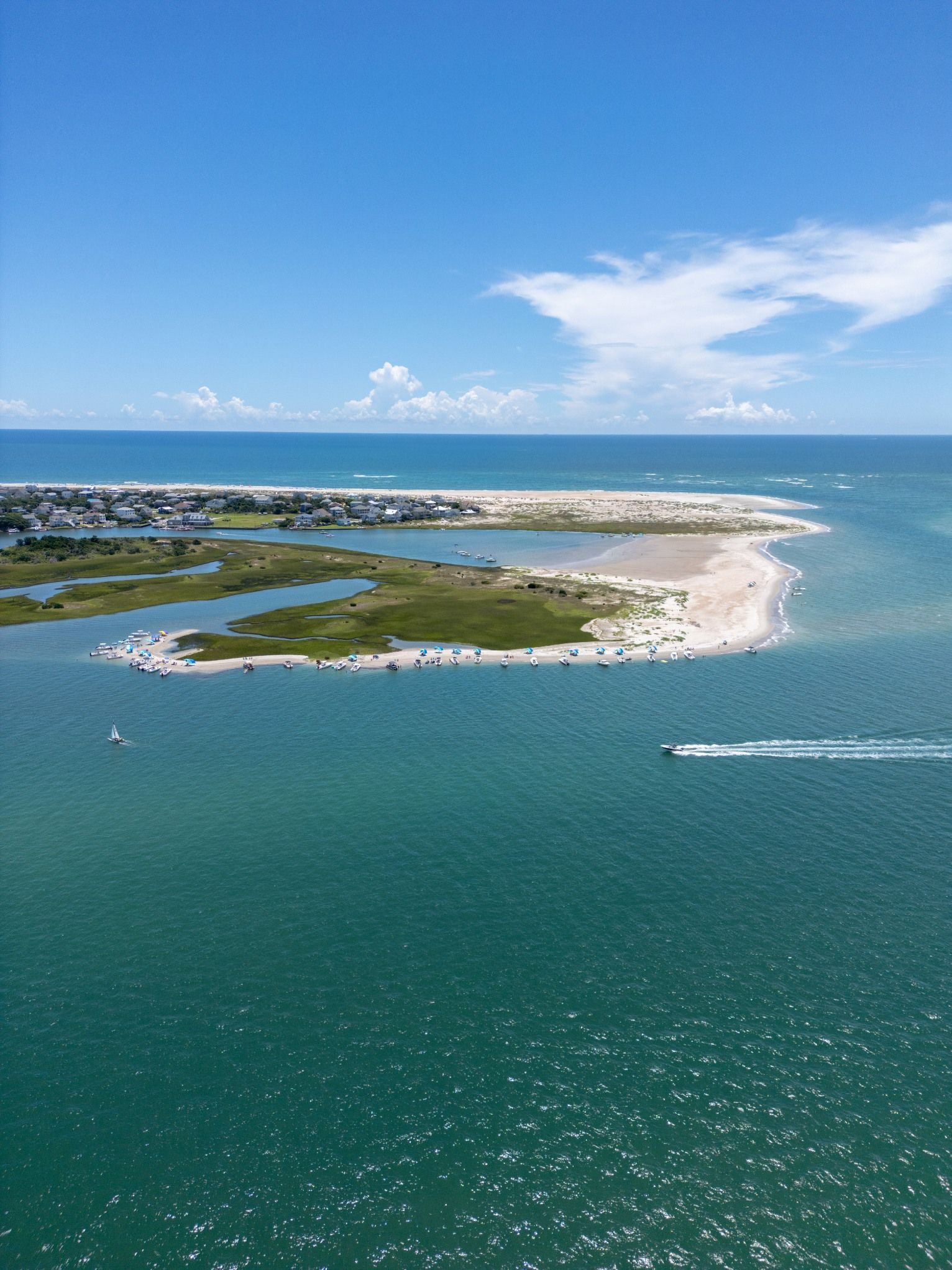 Aerial view of a sandy island surrounded by turquoise water under a blue sky