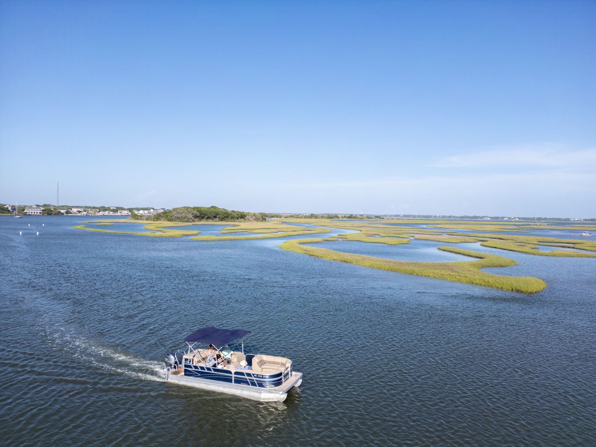 Small boat on blue water near marshy islands under a clear sky
