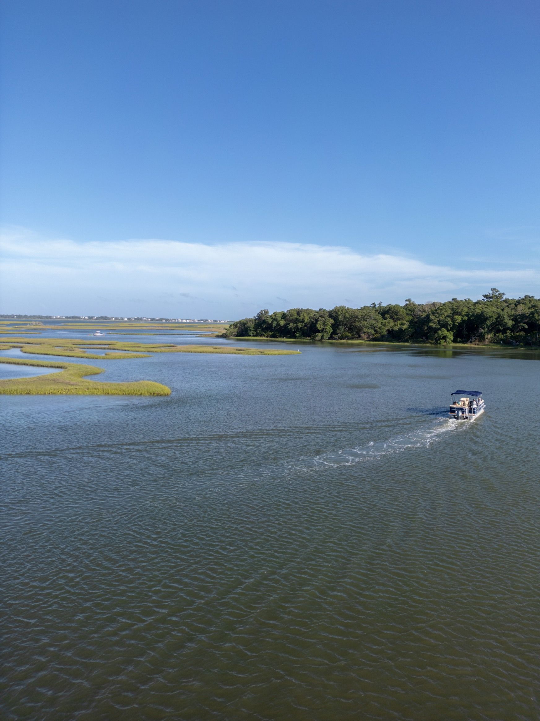 Small motorboat speeding across a wide blue wetland under a clear sky