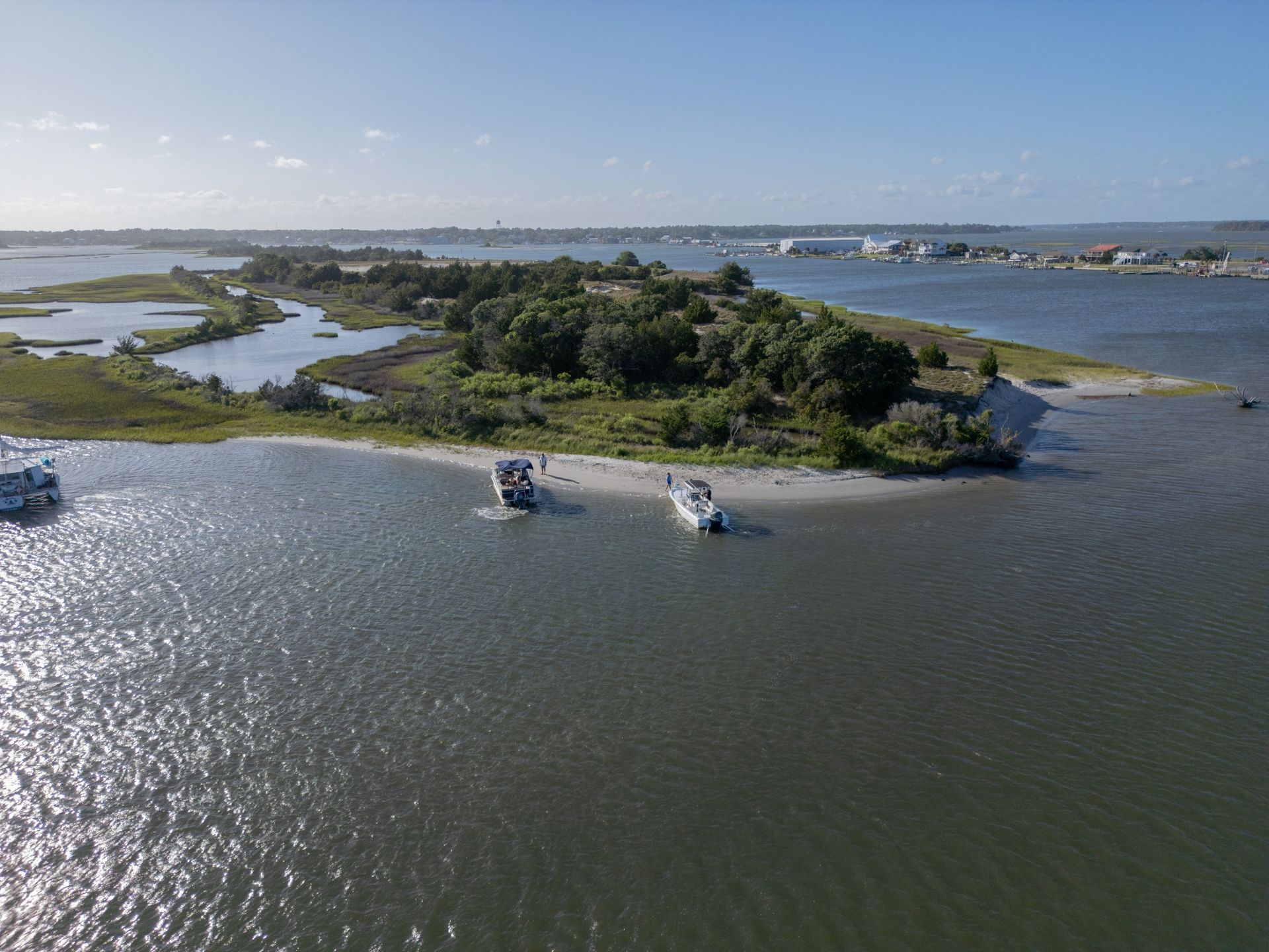 Small boats on a wide river near a green island under a clear sky
