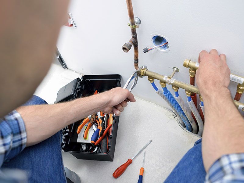 a man is fixing a pipe with a wrench in a bathroom .